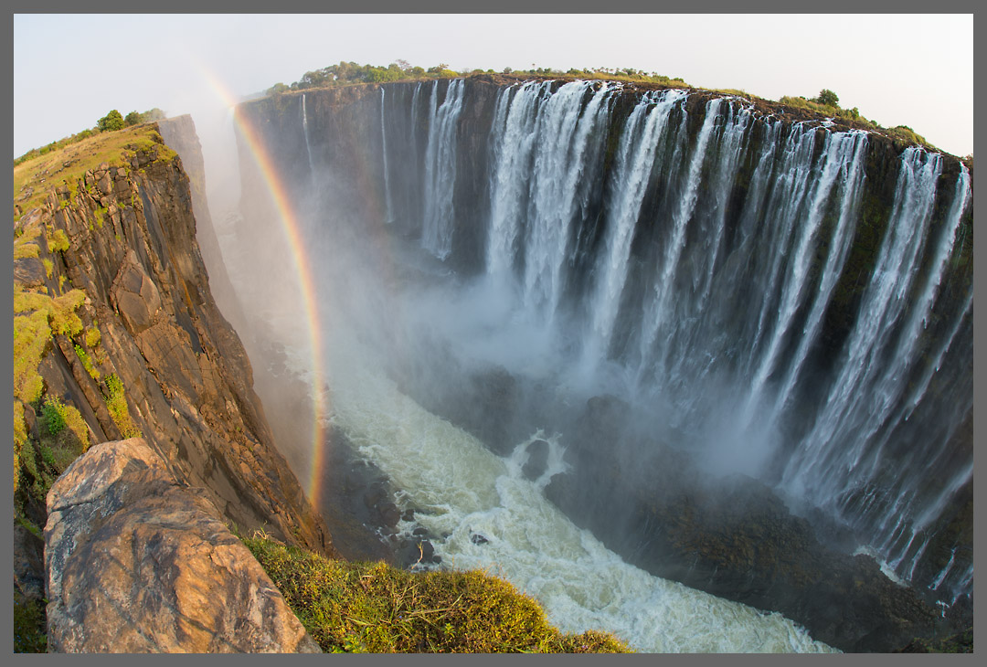 Victoria Falls I - Auf 1700 Metern Breite fällt das Wasser des Sambesi bis 119 Meter in die Tiefe. Die Fälle bestehen aus vier Abschnitten. Dies sind die Main Falls. Die Abbruchkante gehört zu Sambia, die gegenüberliegende Seite der Schlucht zu Simbabwe.